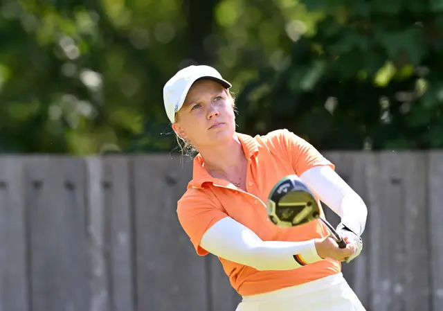 Celina Sattelkau: Schwungfinish im orangen Polo mit weißem Visor vor Holzwand