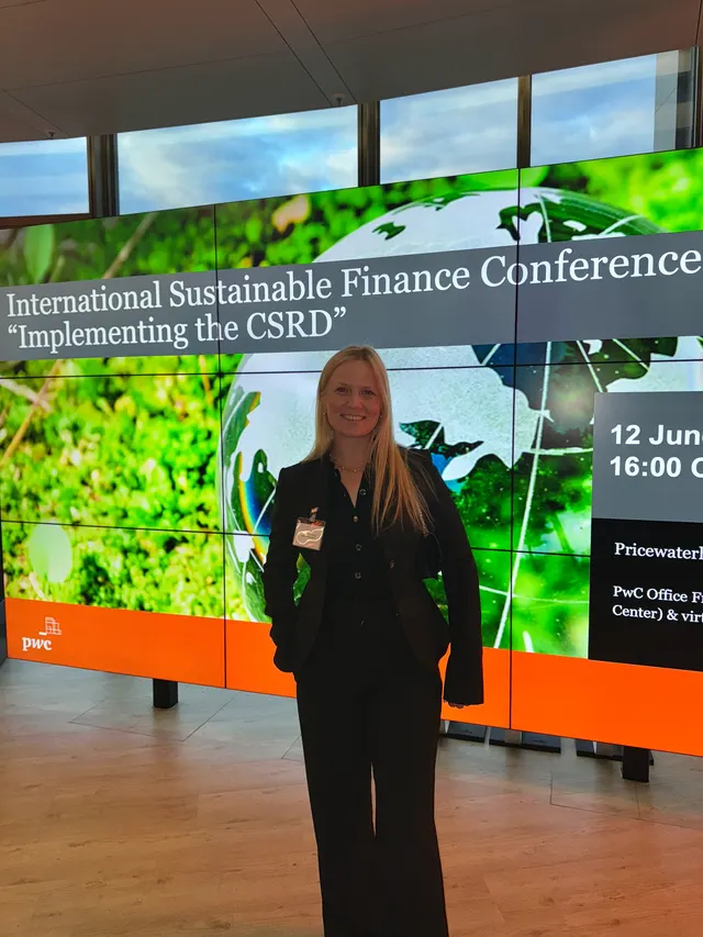 Celina Sattelkau: im schwarzen Blazer vor Leinwand der International Sustainable Finance Conference bei PwC