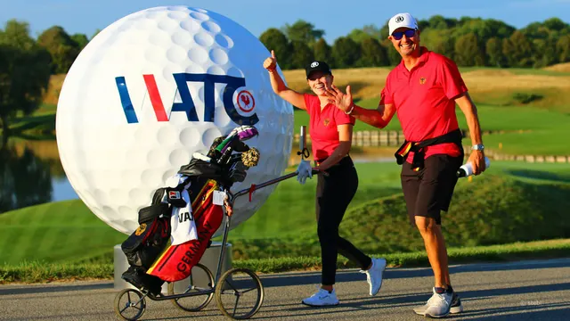 Celina Sattelkau: in Rot mit Trolley neben dem Coach vor einem riesigen WATC-Golfball
