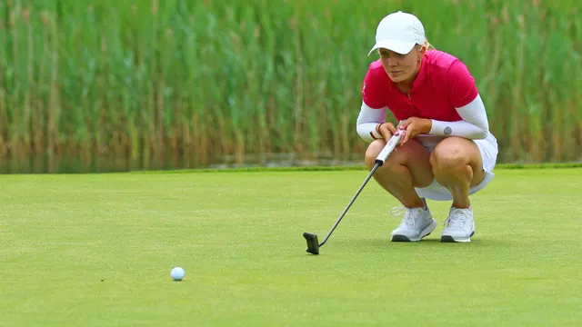 Celina Sattelkau: hockt hinter dem Ball und liest die Puttlinie, pinkes Polo und weißer Rock