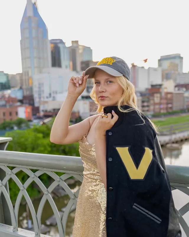 Celina Sattelkau: fasst an ihre Vanderbilt-Cap, goldenes Kleid und College-Jacke, Skyline von Nashville