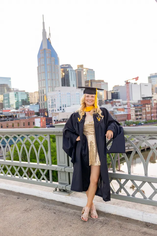 Celina Sattelkau: im Talar mit Hut auf einer Brücke, goldenes Kleid, Skyline von Nashville