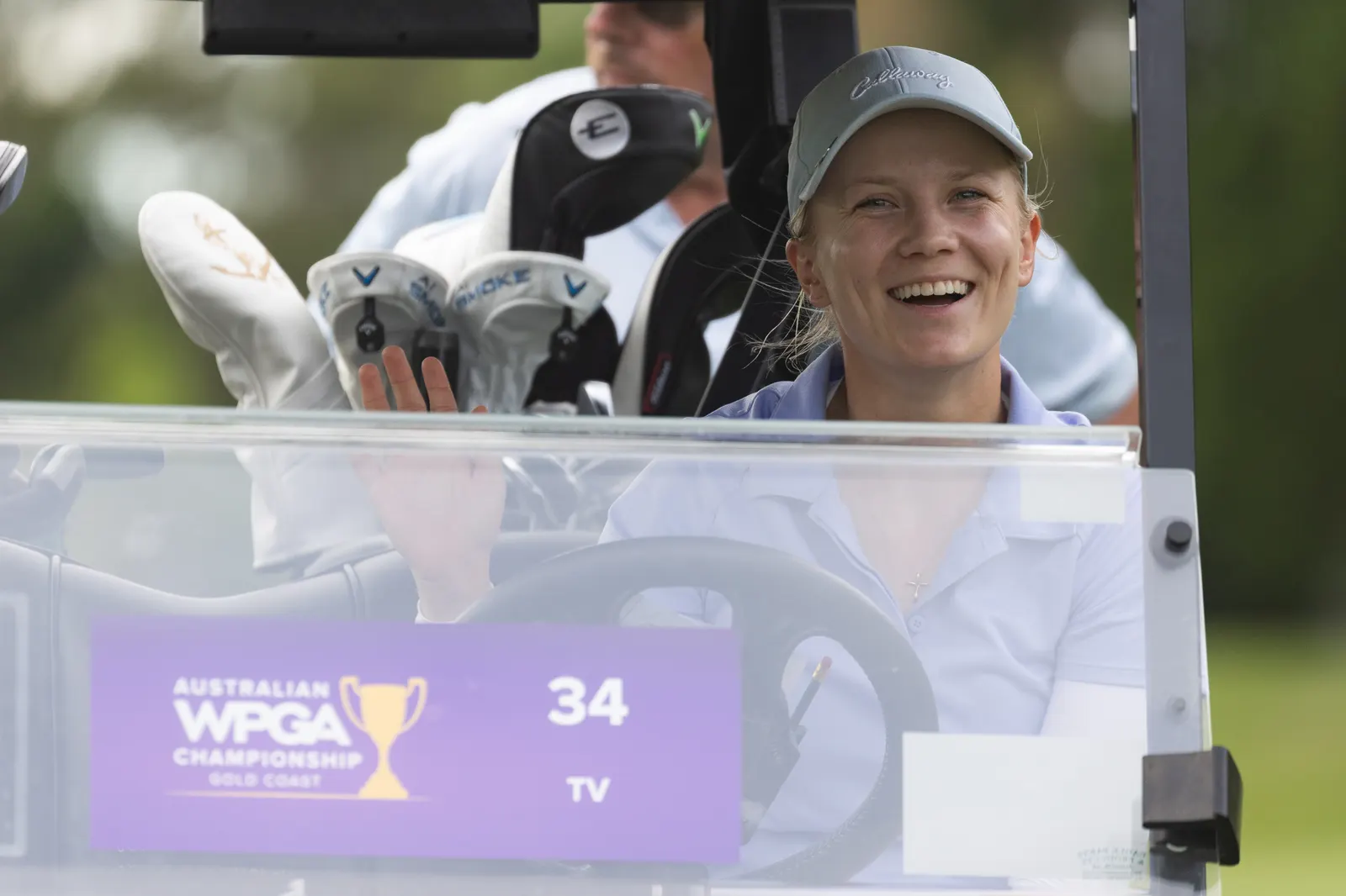 Celina Sattelkau lacht im Golfcart neben dem Schlägerbag